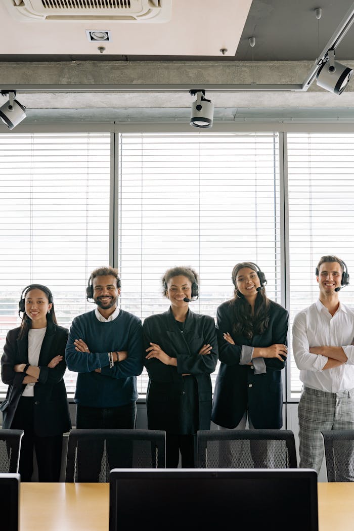A diverse group of call center professionals with headsets posing confidently in a modern office setting.